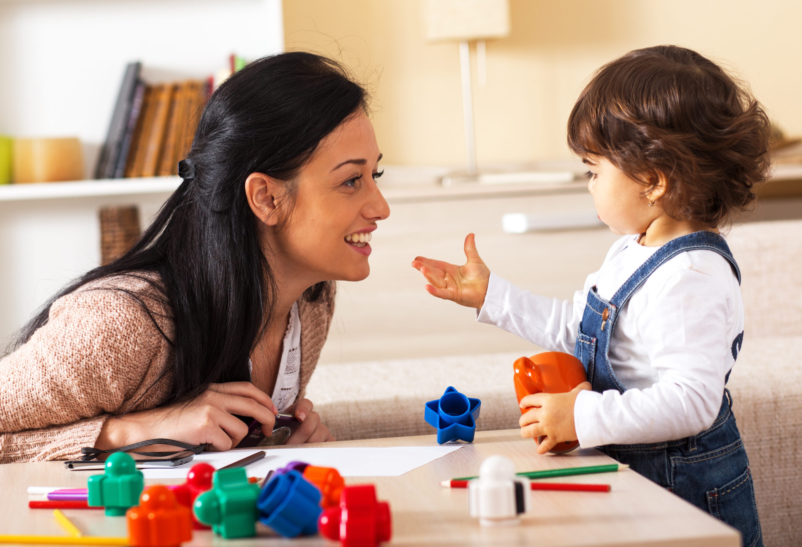 Mother and baby girl playing with toys in living room.